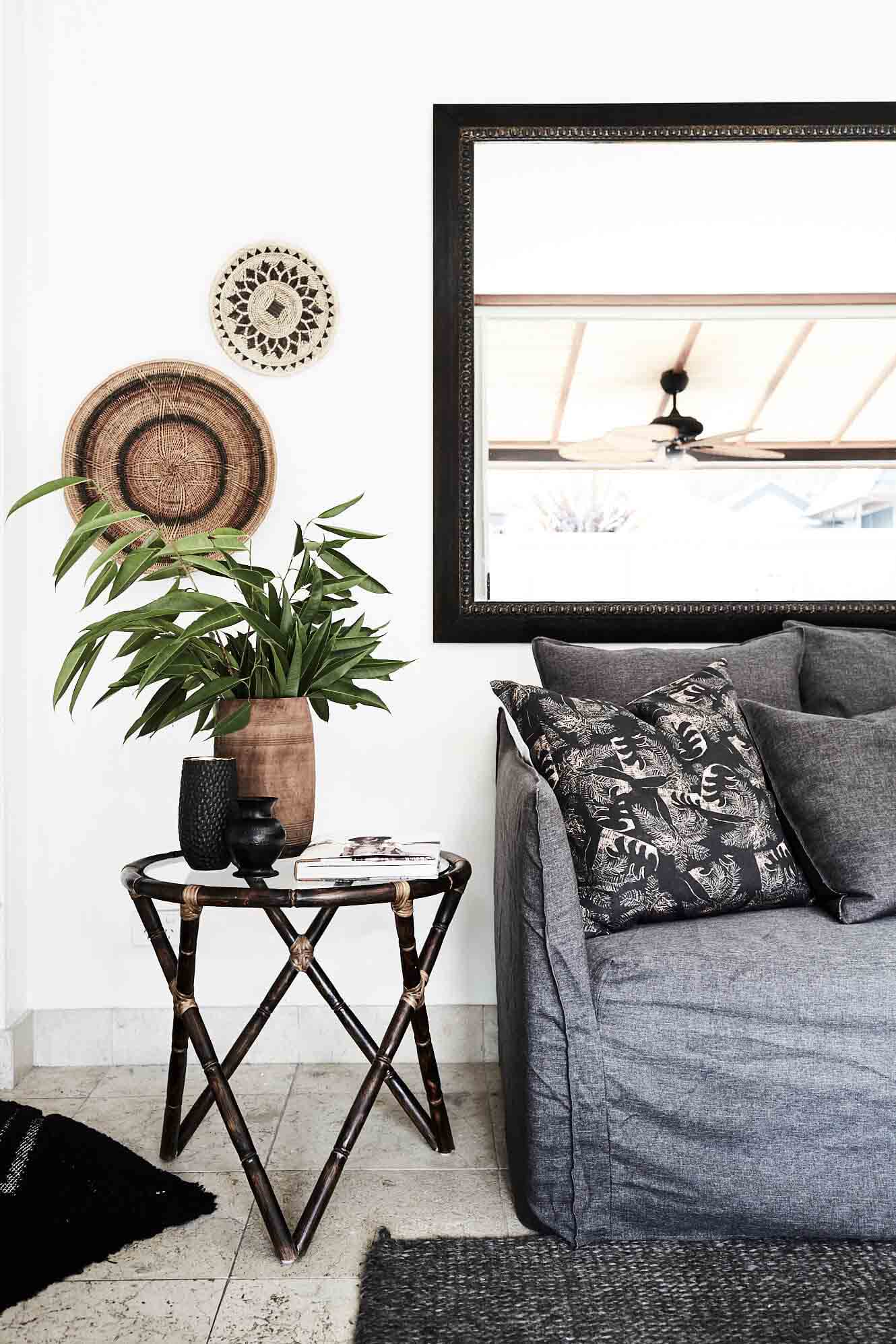 Interior styling at The Villas of Byron with a mix of linen lounge, cane side table, indoor plants, rustic wall hangings and oversize mirrors