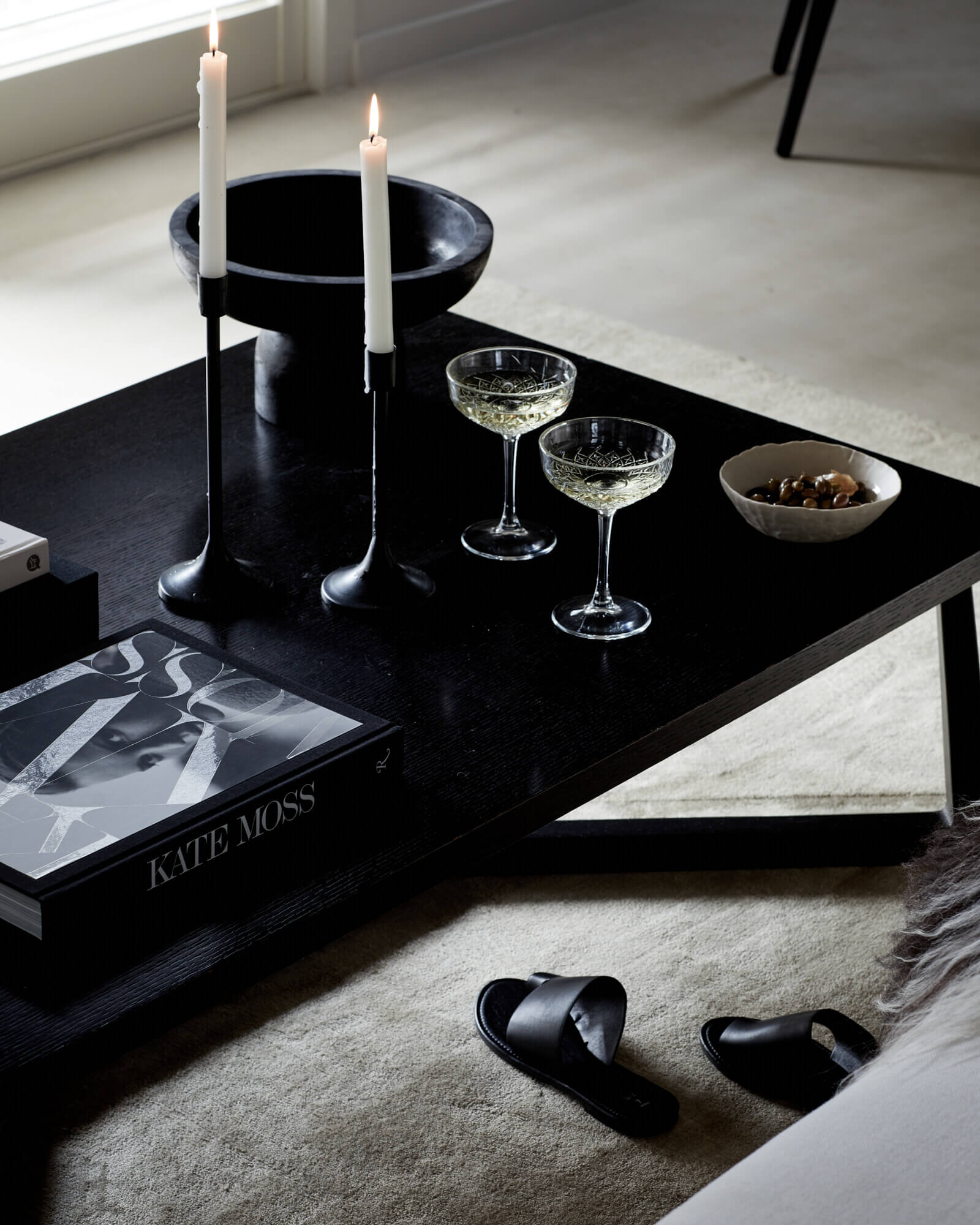 Contemporary coffee table with lit candles, champagne and nibbles