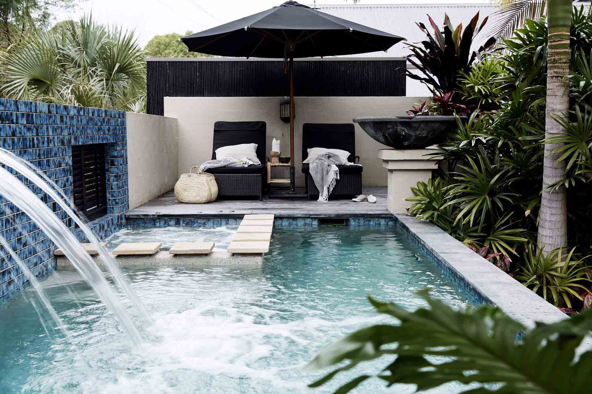Black umbrella and daybeds next to the private pool, waterfall and heated spa at The Villas of Byron