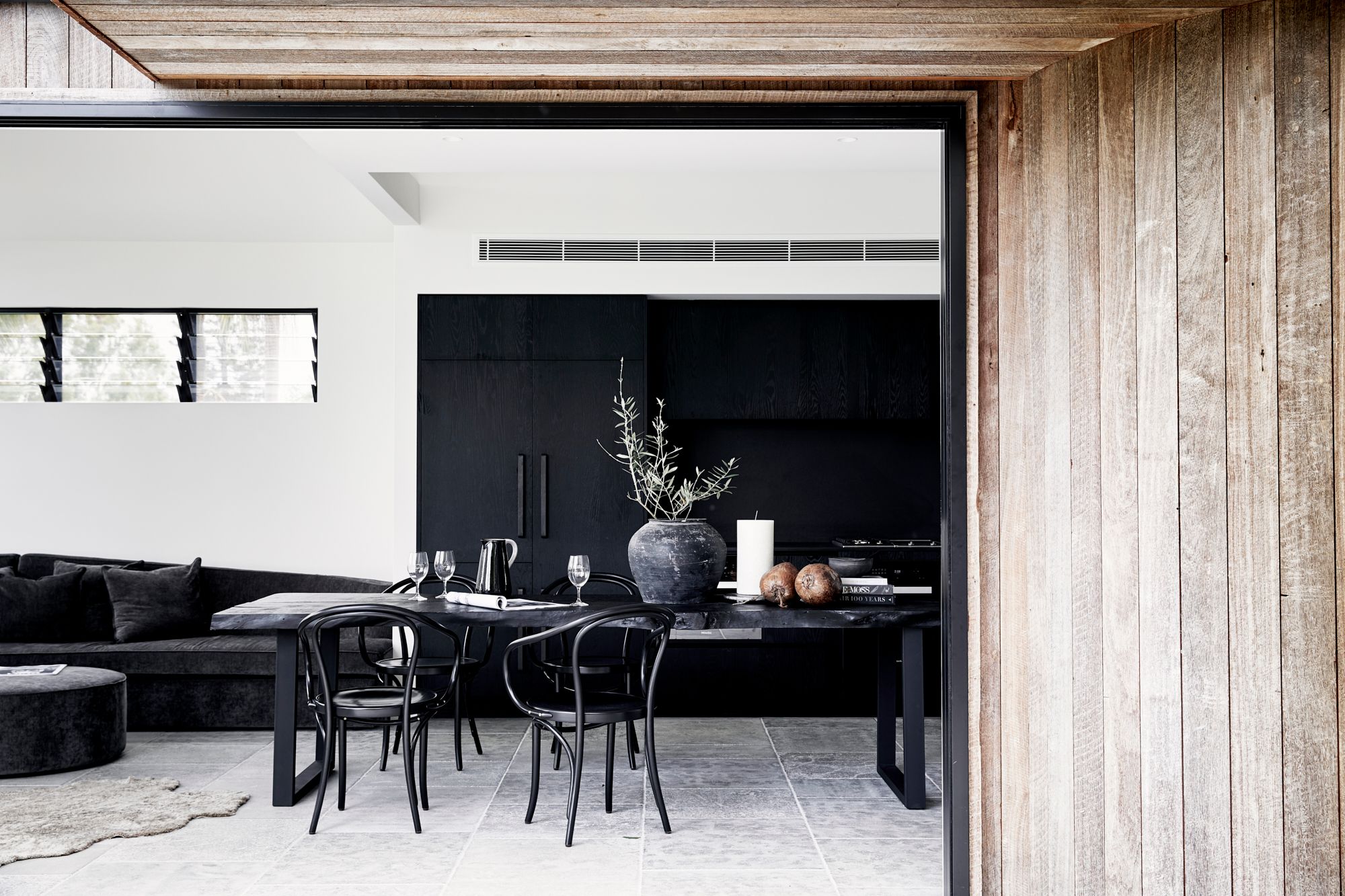 Charred black timber dining table and black Bentwood chairs in the dining room at The Cabin, Byron Beach Abodes