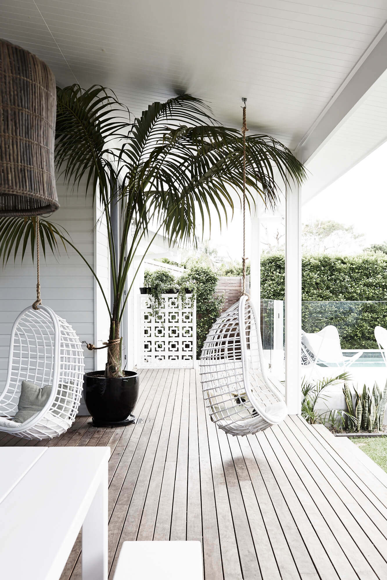 Outdoor living area with hanging cane chairs at Magnolia House, Byron Beach Abodes