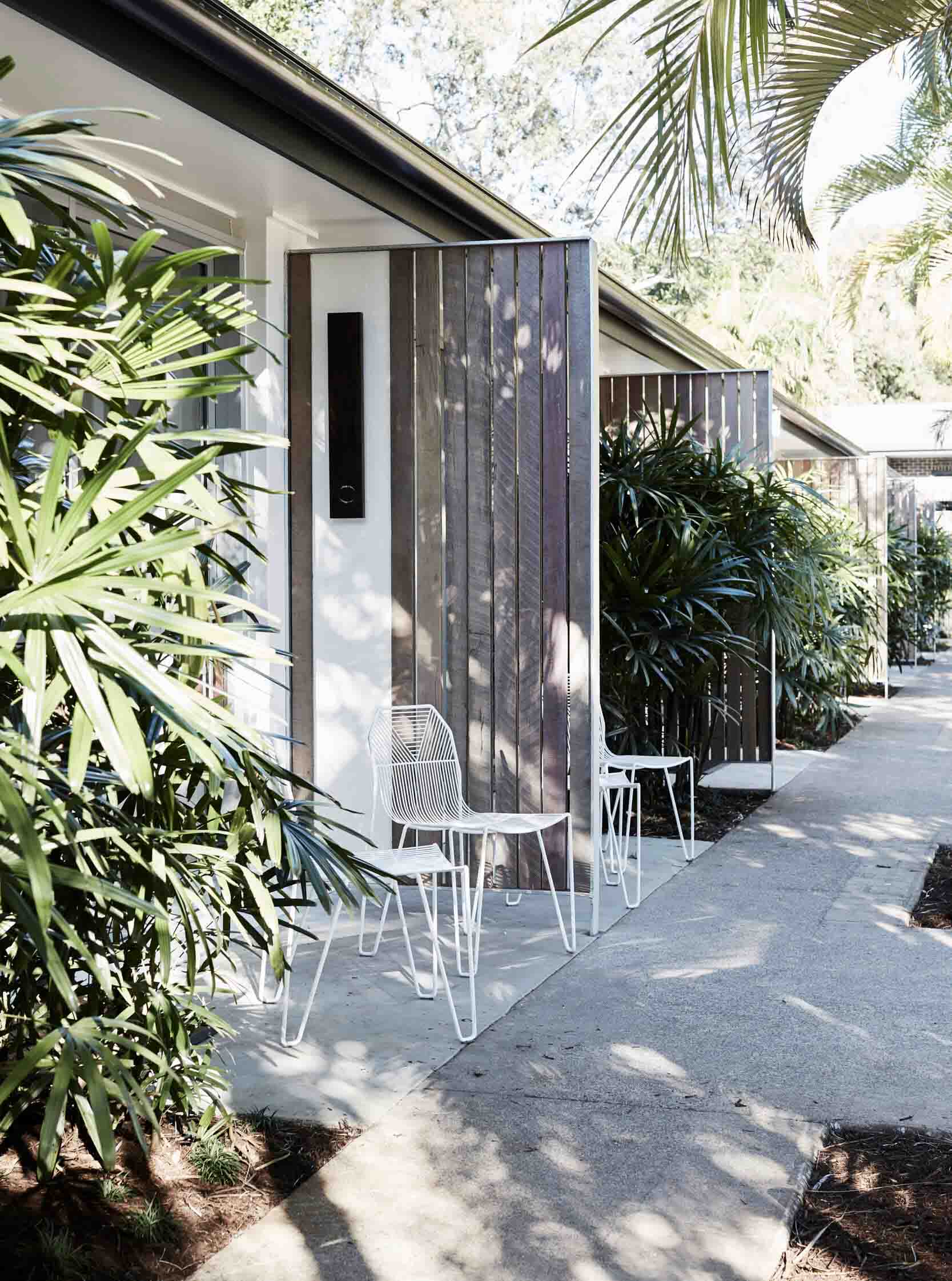 Entrance to the Bower Suites, The Bower Byron Bay hotel with large Raphis Palms and white metal seating