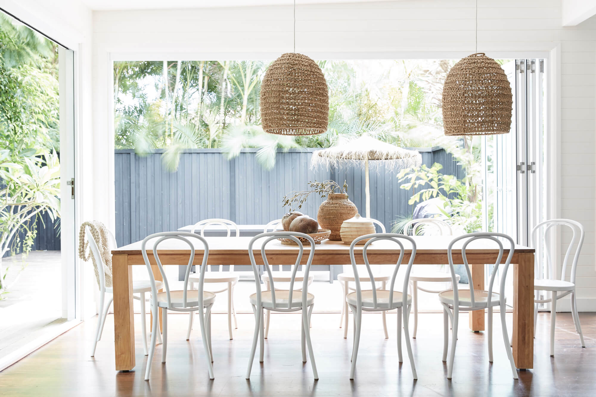 Timber dining table and white Bentwood chairs in dining room at The Cottage, The Bower Byron Bay