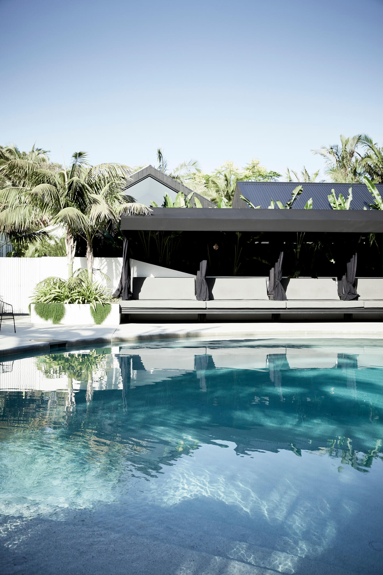 Long covered daybeds next to the blue mineral pool at The Bower Byron Bay