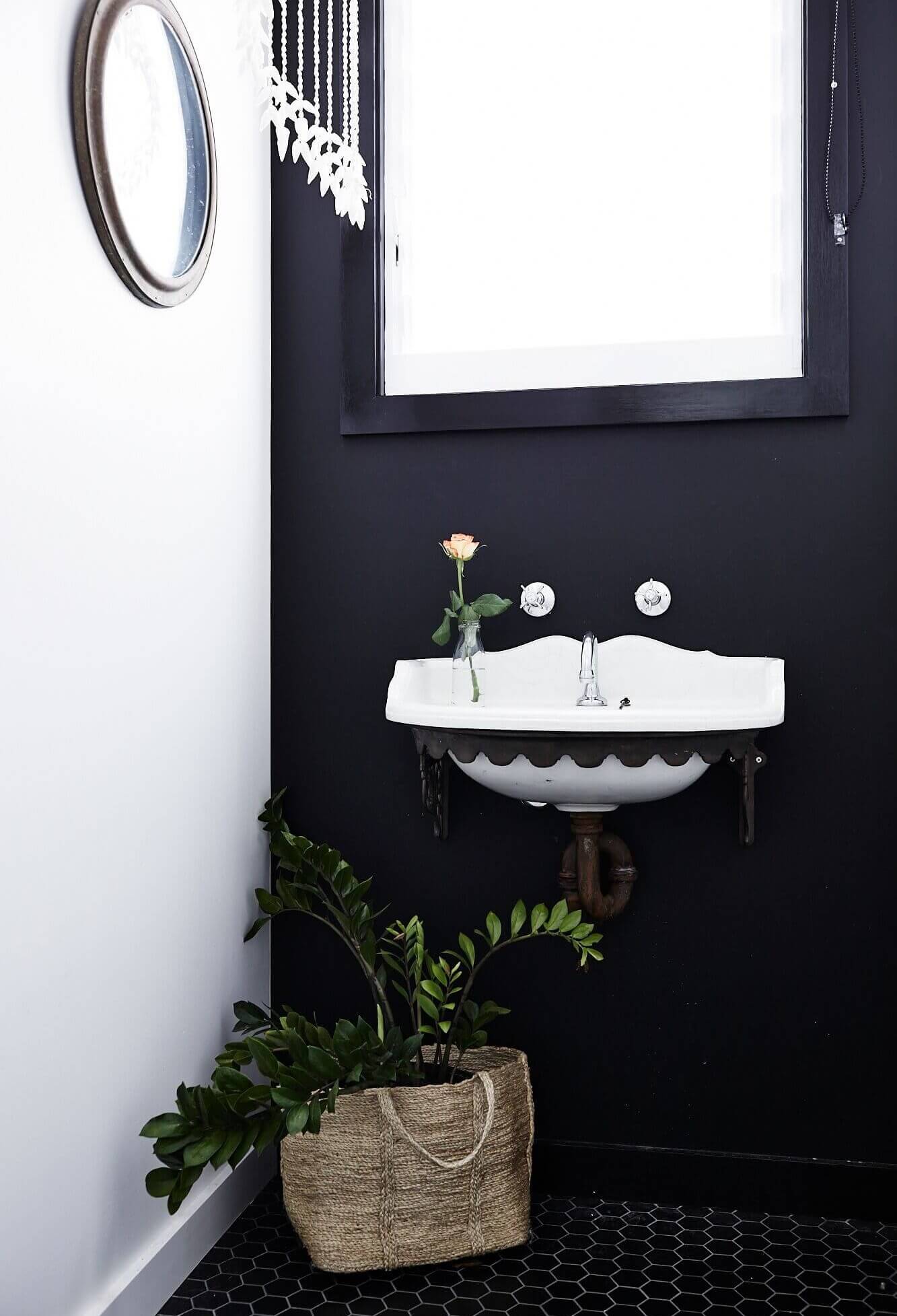 Powder room at Magnolia House, Byron Beach Abodes with vintage vanity basin and tapware, black wall and black tiled floor