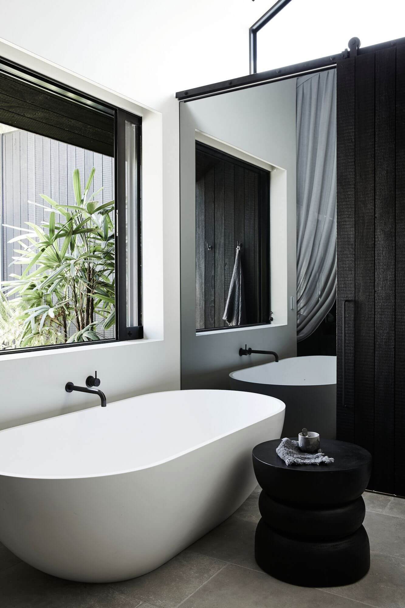 Ensuite overlooking the private courtyard at Bower Studios at The Bower Byron Bay hotel with stone bathtub and full mirror wall