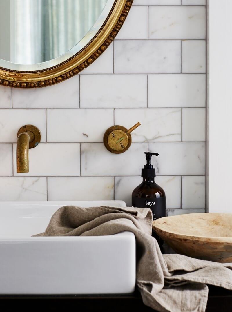 Bathroom details from The Chalet, Byron Beach Abodes featuring marble subway tiles, brass tapware and gold gilt mirror